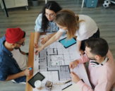 a group of people sitting around a table working on a project